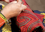 Woman's hands embroidering colorful fabric.